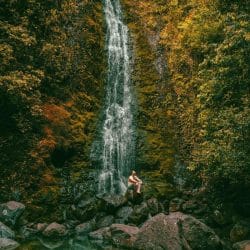 Man sitting near waterfall in Hawaii Man sitting near waterfall in Hawaii
