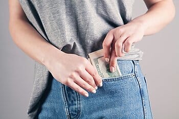 woman puts money in her pocket as featured image for Wonder Voyage blog on how to save money by securing your 2026 adventure now