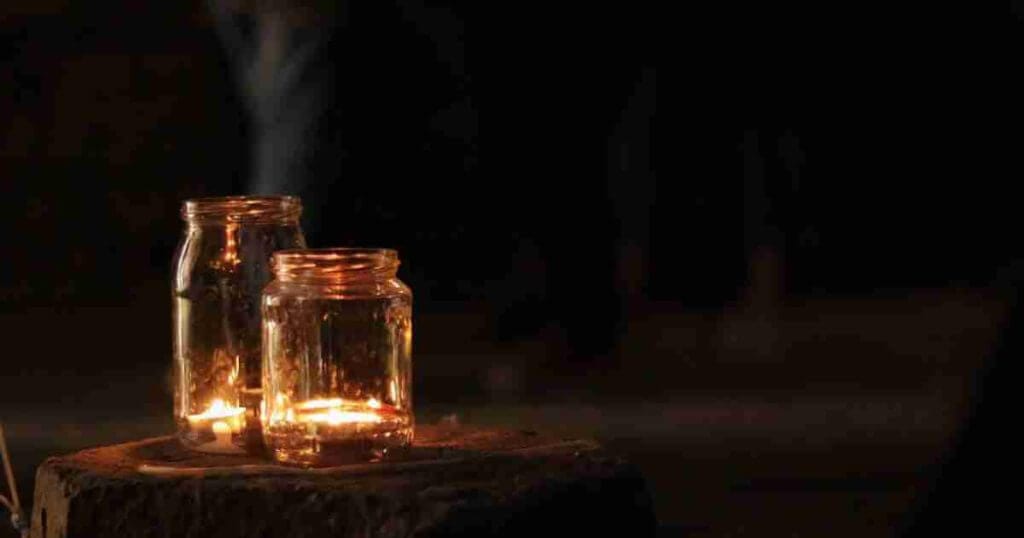 Wonder Moment: Saying Goodbye Two jars with lit tea candles in them sitting on a wood stump at night.