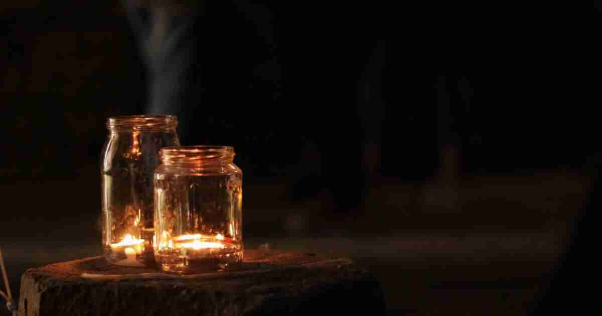 Wonder Moment: Saying Goodbye Two jars with lit tea candles in them sitting on a wood stump at night.
