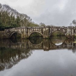 Crossing a Roman bridge along the Tokens left on a marker along the Camino de Santiago on a pilgrimage with Wonder Voyage.