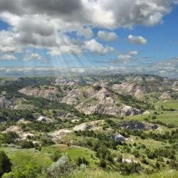 image of sun shining through clouds on mountains in North Dakota for wonder Voyage blog about Christian pilgrimage in the USA