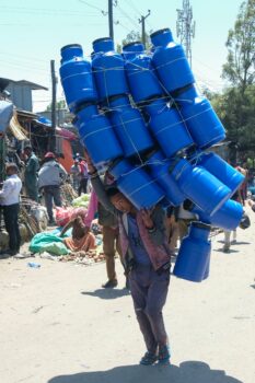 man carries countless blue jugs on his shoulder for blog post about planning a transformational mission trip