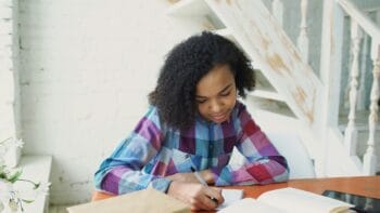 teen writing in notebook for blog about youth mission trip fundraising ideas
